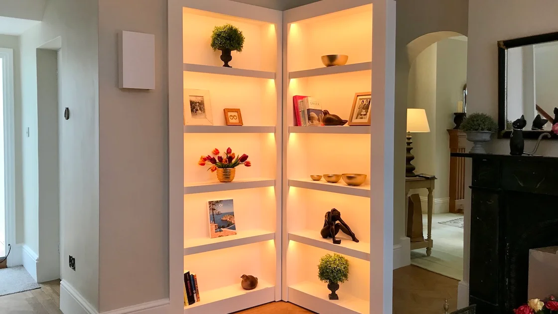 Stylish illuminated hidden door shelving unit display.